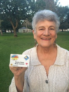 Suzie Heap holds up her master gardener card, which notes more than 2,000 hours of volunteerism and experience.